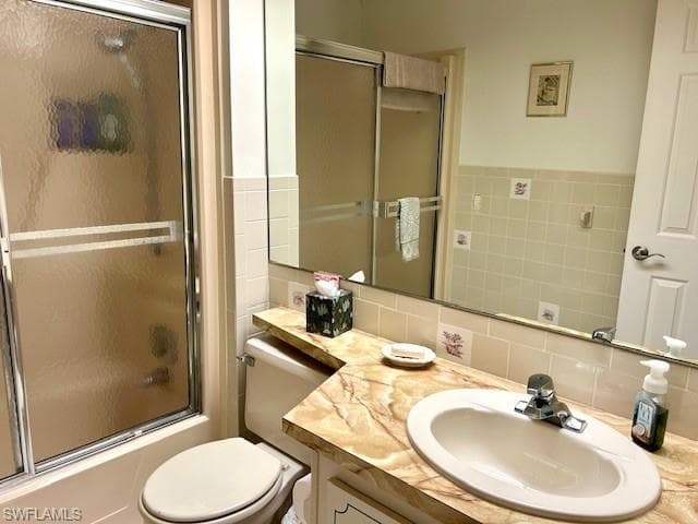 Bathroom featuring combined bath / shower with glass door, vanity, and backsplash