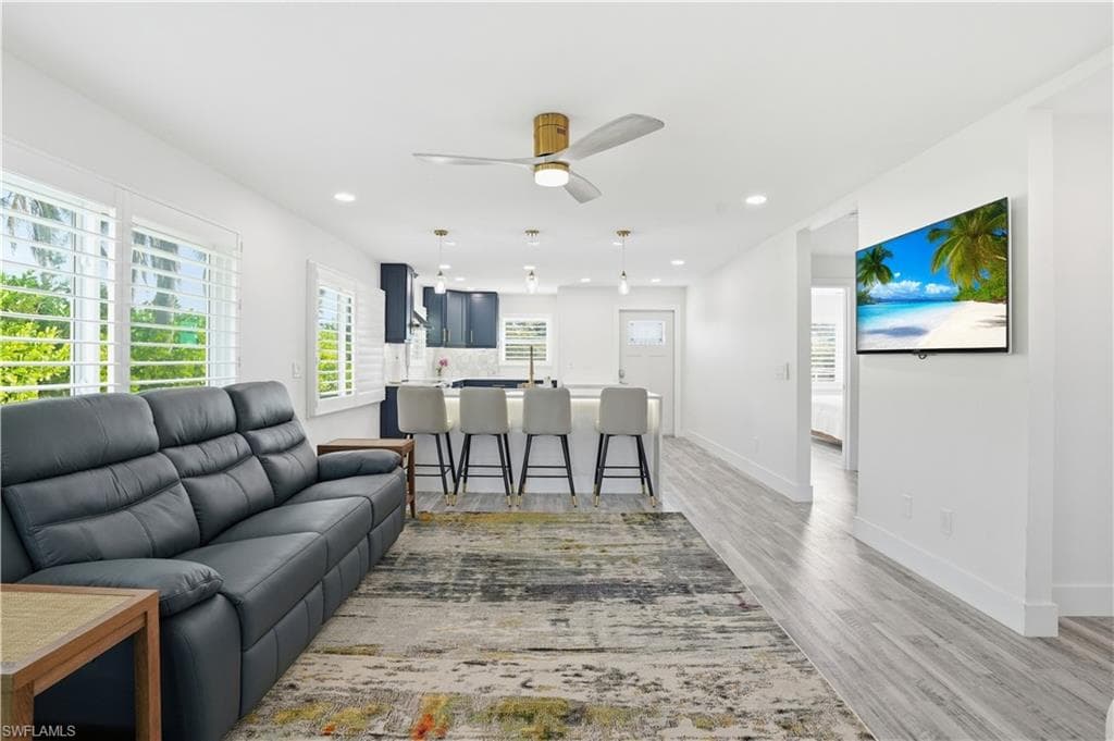 Living area with light wood-type flooring, ceiling fan, and recessed lighting - Virtually Edited Image