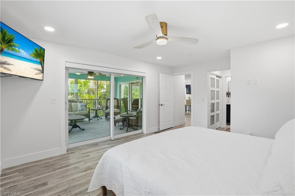 Bedroom featuring light wood-style flooring, ceiling fan, recessed lighting, and access to exterior - Virtually Edited Image