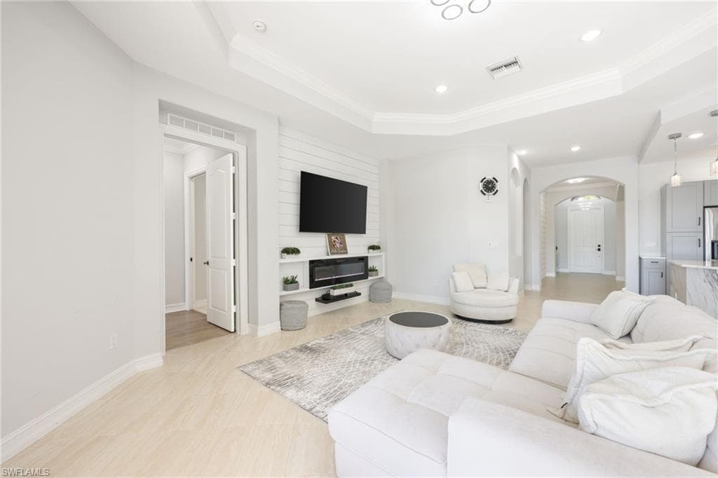 Living area featuring light wood-finish flooring, a tray ceiling, and recessed lighting