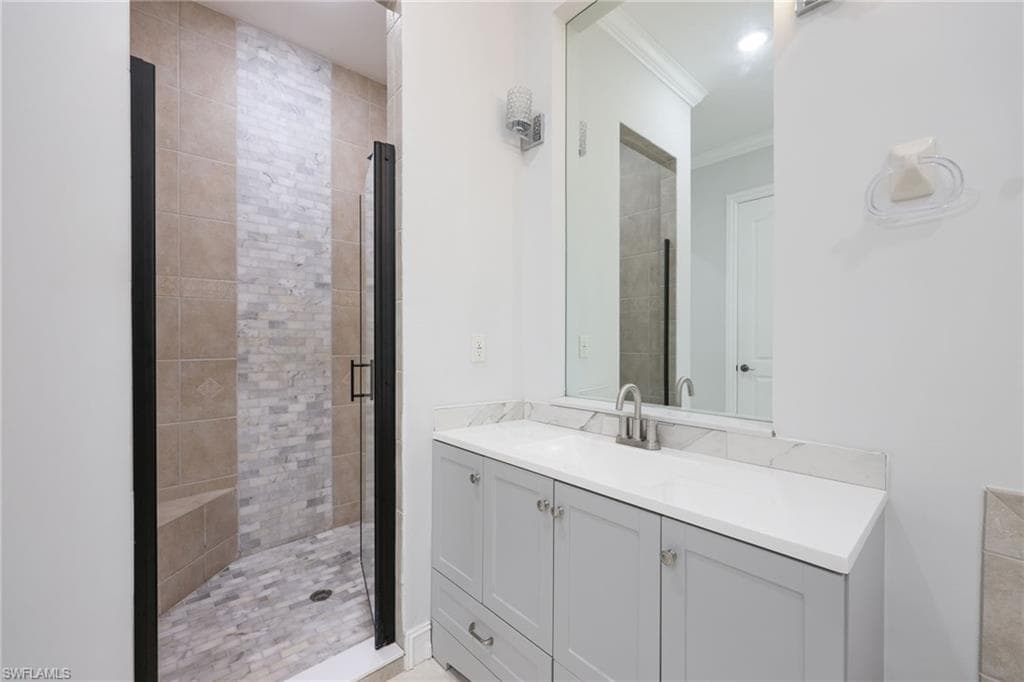Bathroom vanity featuring a light gray cabinet with brushed nickel hardware, a white countertop, and a rectangular mirror