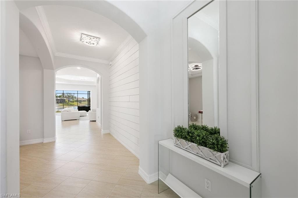 Entryway featuring light-toned tile flooring, archways, and a shiplap accent wall