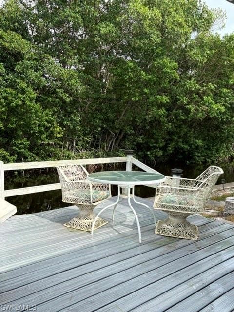 Expansive wooden deck featuring a white railing and tranquil water views