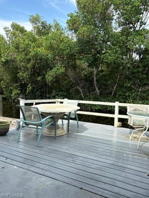 Expansive outdoor deck featuring composite decking, a white railing system, and dense tropical foliage bordering a waterway