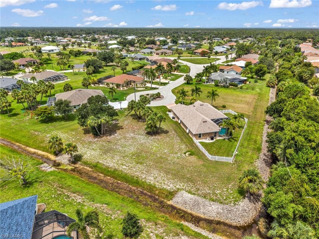 Expansive residential neighborhood featuring numerous single-story homes, mature tropical landscaping, and a curvilinear street layout