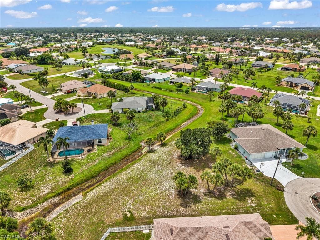 Aerial perspective showcasing a residential community with numerous single-story homes, mature palm trees, and verdant landscaping