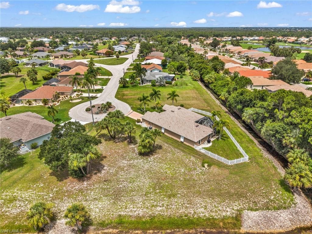 Spacious property featuring a single-story home with a screened lanai and pool, surrounded by mature palm trees