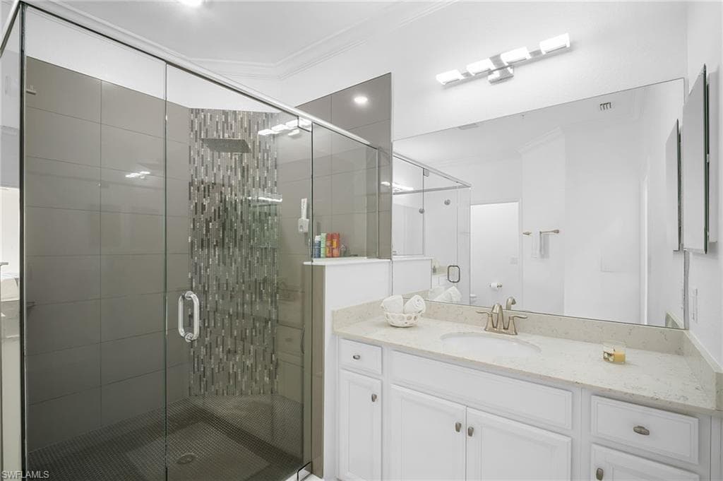 Walk-in shower with clear glass enclosure, a rainfall showerhead, and decorative accent tile