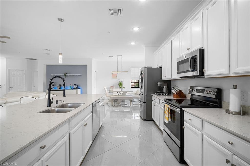 Spacious kitchen featuring white cabinetry, light-toned countertops, and an undermount double basin sink with a matte black faucet