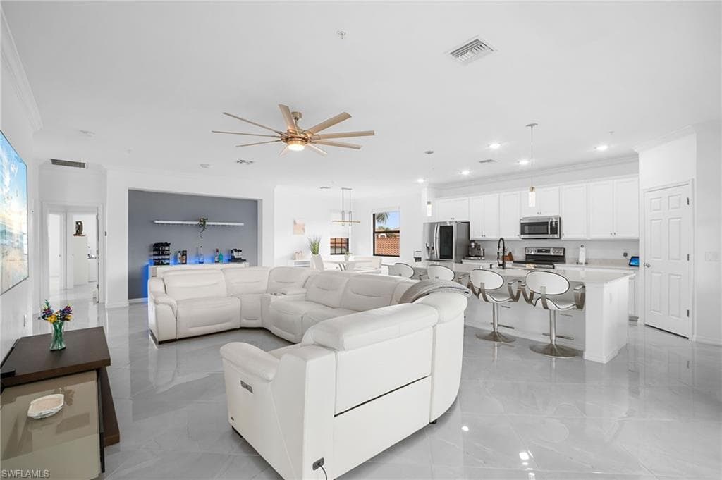 Expansive open-concept living area featuring large format tile flooring, a contemporary ceiling fan, and recessed lighting
