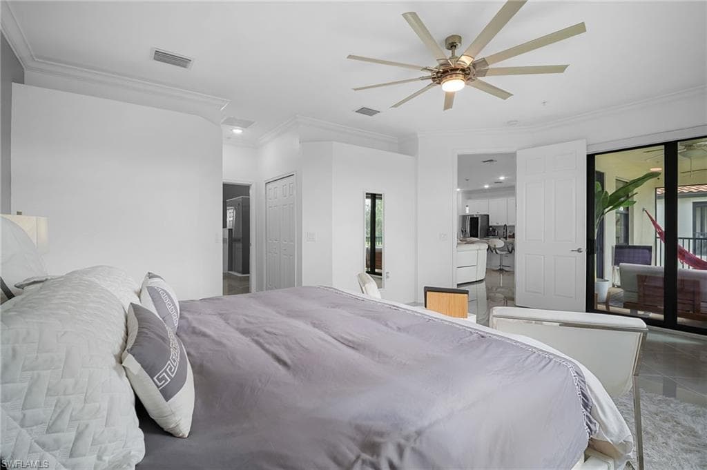 Spacious interior featuring crown molding, a multi-blade ceiling fan with integrated lighting, and direct access to an outdoor living area through sliding glass doors