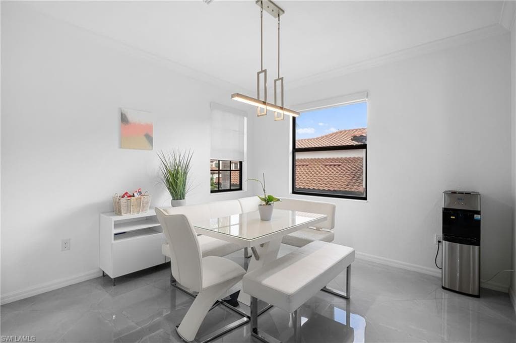 Dining area featuring a modern linear chandelier, two windows with white roller shades, and polished gray tile flooring