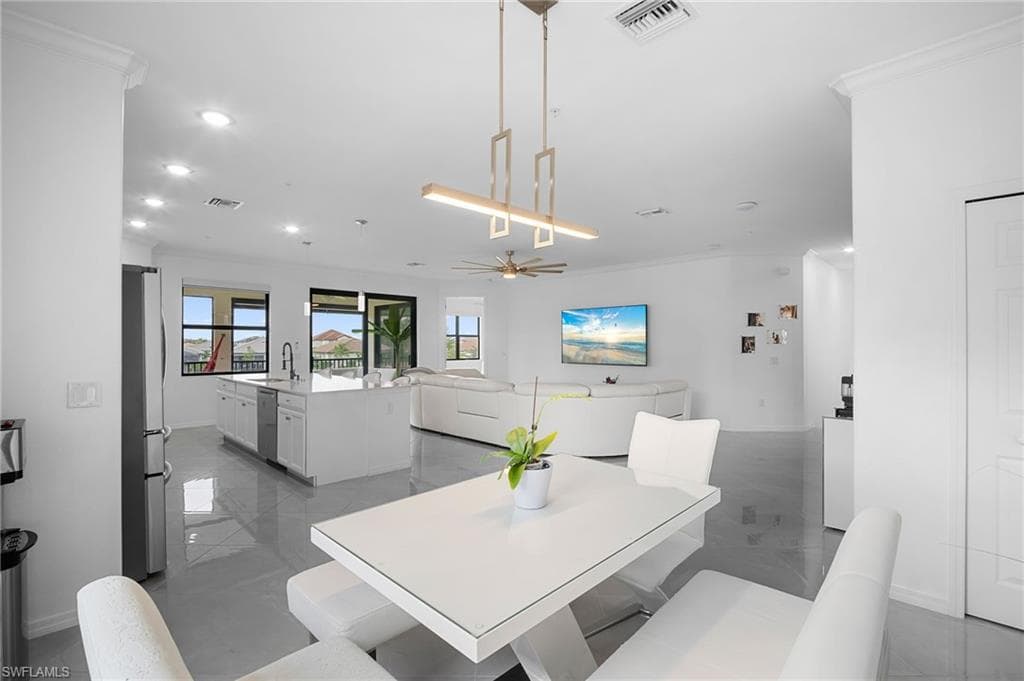 Open-concept living space featuring a spacious kitchen island, stainless steel refrigerator, recessed lighting, and large windows