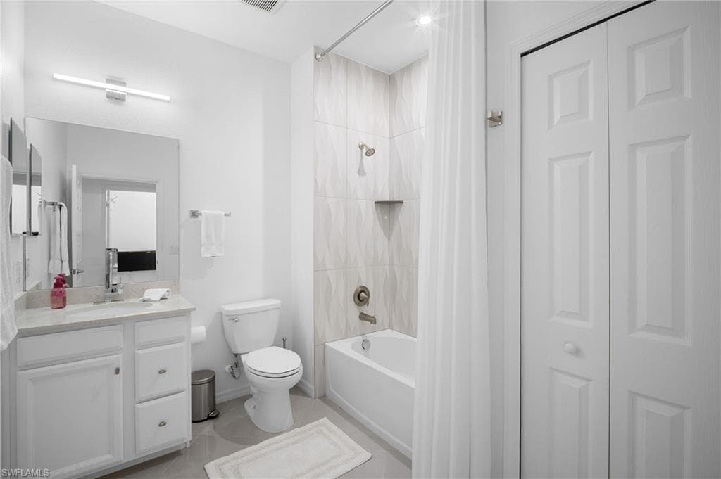Bathroom featuring a white vanity with a light-toned countertop, a large mirror, and a shower-tub combination with textured tile surround