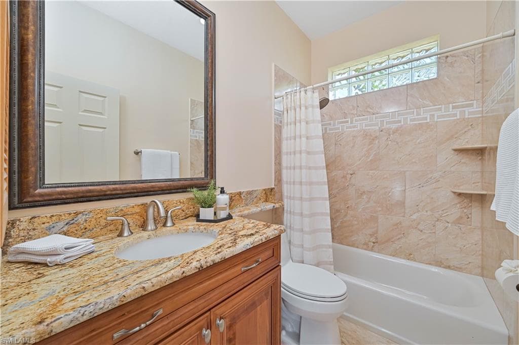 Bathroom vanity featuring a polished stone countertop with an undermount sink and brushed nickel faucet