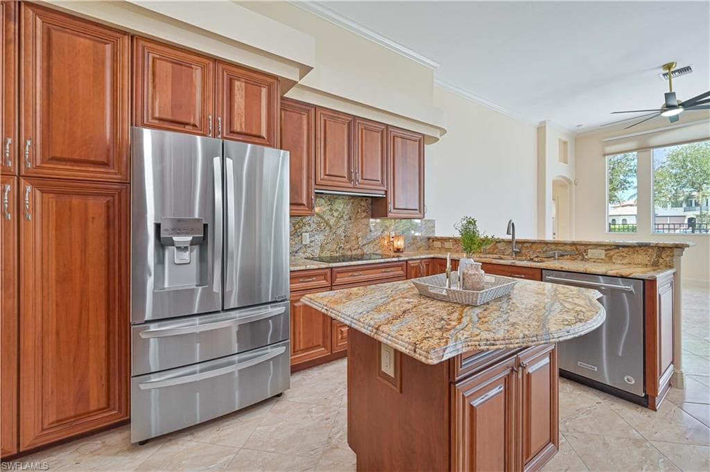 Gourmet kitchen featuring a stainless steel French door refrigerator, cherry wood cabinetry, a granite countertop island with a curved edge, and tile flooring