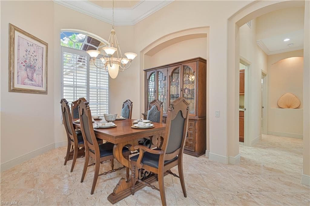 Dining area featuring marble-finish flooring, an arched entryway, and crown molding