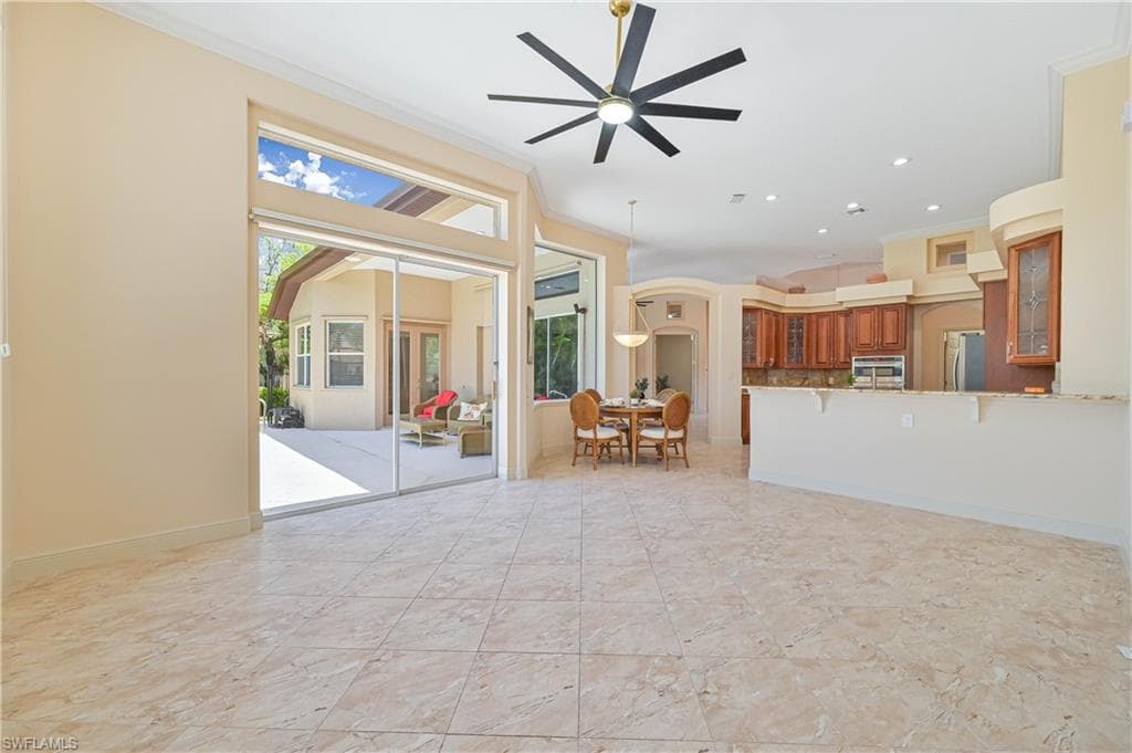 Spacious open-concept interior with large format tile flooring and a multi-blade ceiling fan