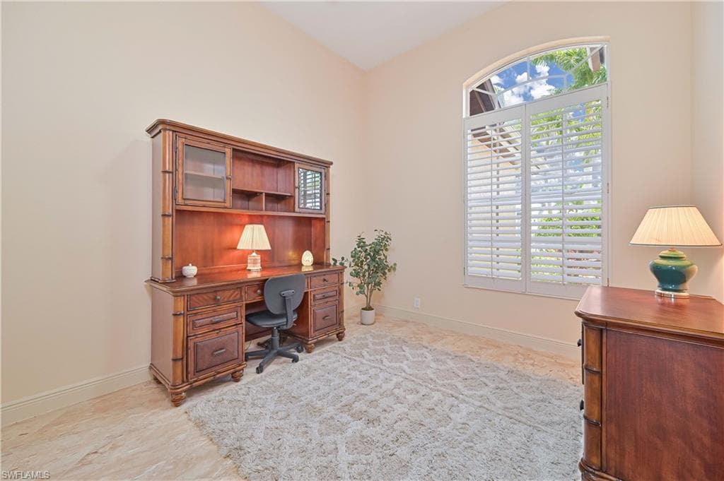 Room featuring a large arched window with plantation shutters, light-toned wall paint, and tile flooring