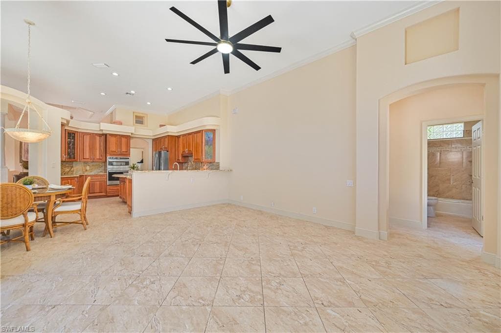 Open-concept living area featuring large format tile flooring, a contemporary ceiling fan, and a kitchen with wood cabinetry and a breakfast bar