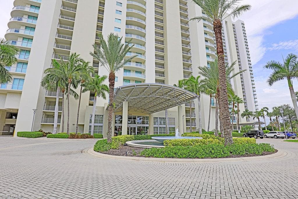 Modern high-rise residential building featuring a grand porte-cochère entrance with a contemporary canopy