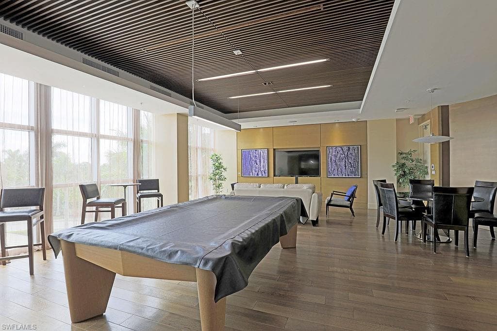 Recreation room featuring a pool table, wood-finish flooring, full-height windows with sheer drapery, and a slatted wood ceiling detail with integrated lighting