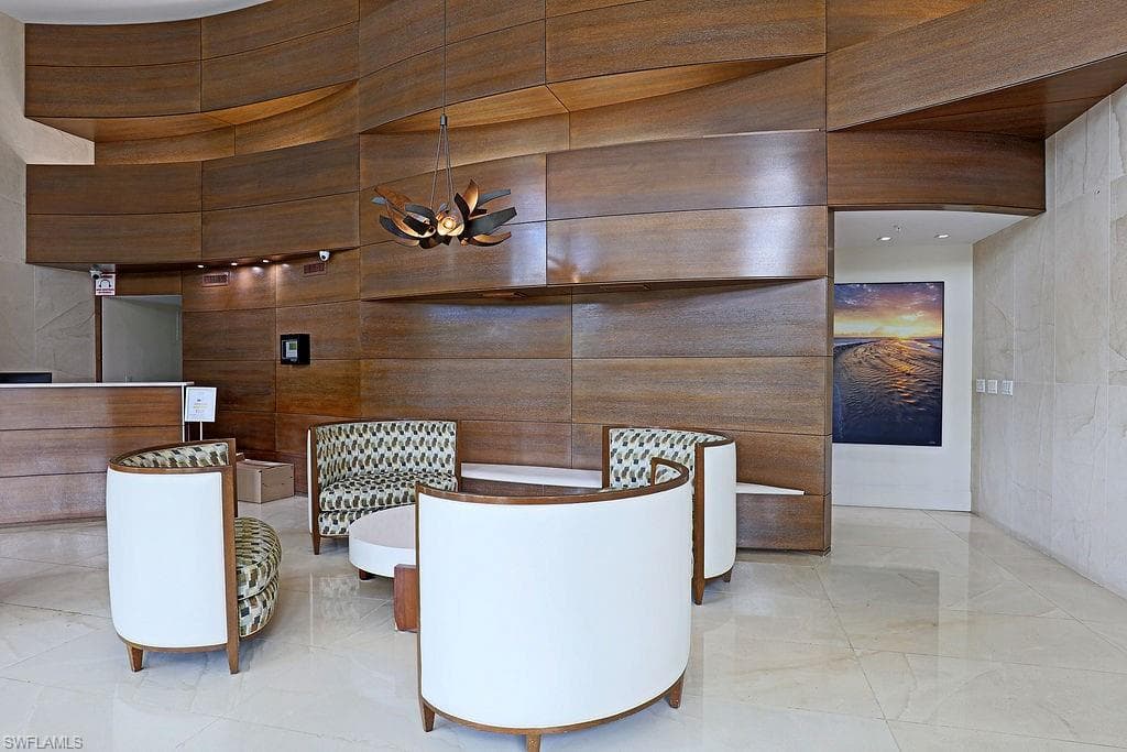 Lobby area featuring wood-finish wall panels with a curved design, a contemporary chandelier, and polished light-toned flooring