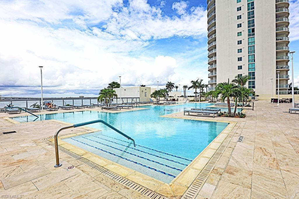 Expansive multi-level swimming pool area featuring a large main pool with integrated steps, surrounded by stone-tile decking