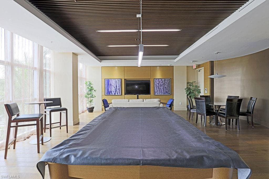 Recreation room featuring an expansive billiards table, wood-finish flooring, and a slatted ceiling with integrated linear lighting