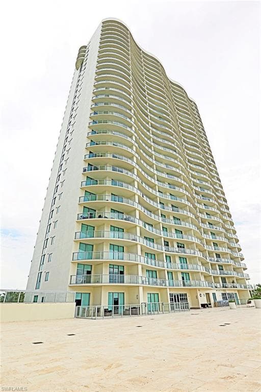 Contemporary high-rise building featuring a striking curved facade with numerous private balconies