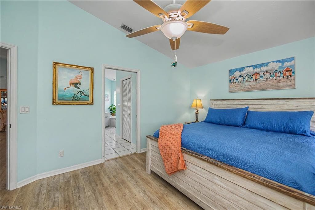 Bedroom featuring wood-finish flooring, vaulted ceilings, and a ceiling fan with light fixture