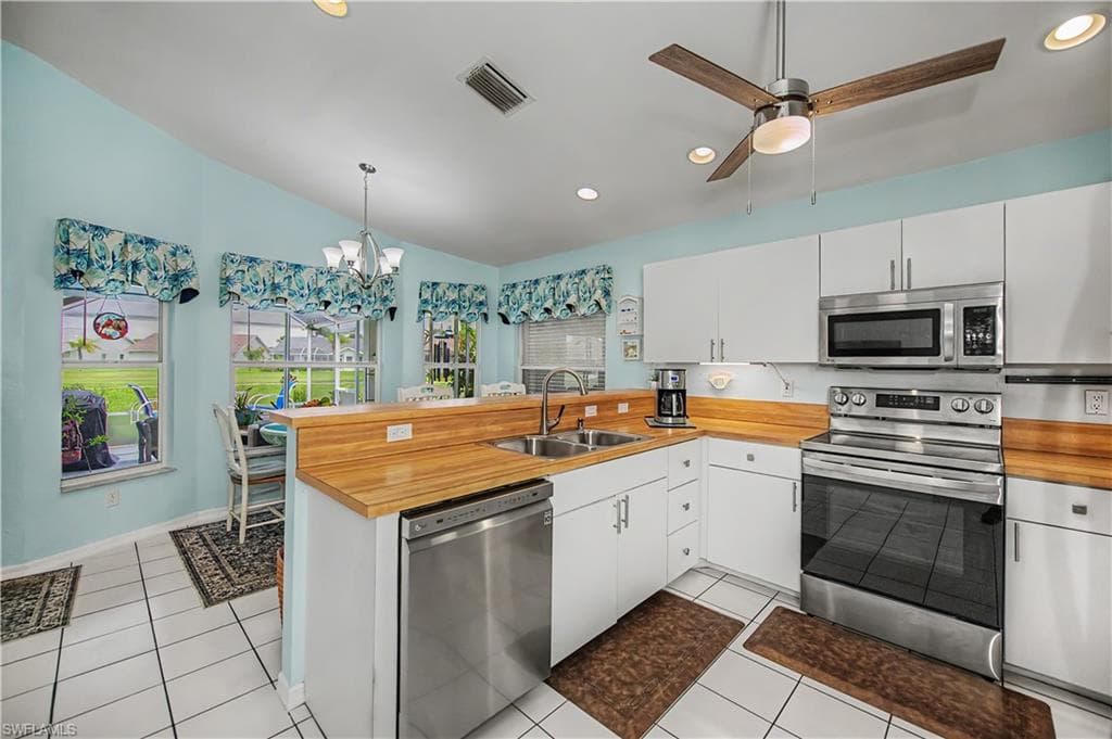 Kitchen featuring white cabinetry, light wood-finish countertops, and stainless steel appliances