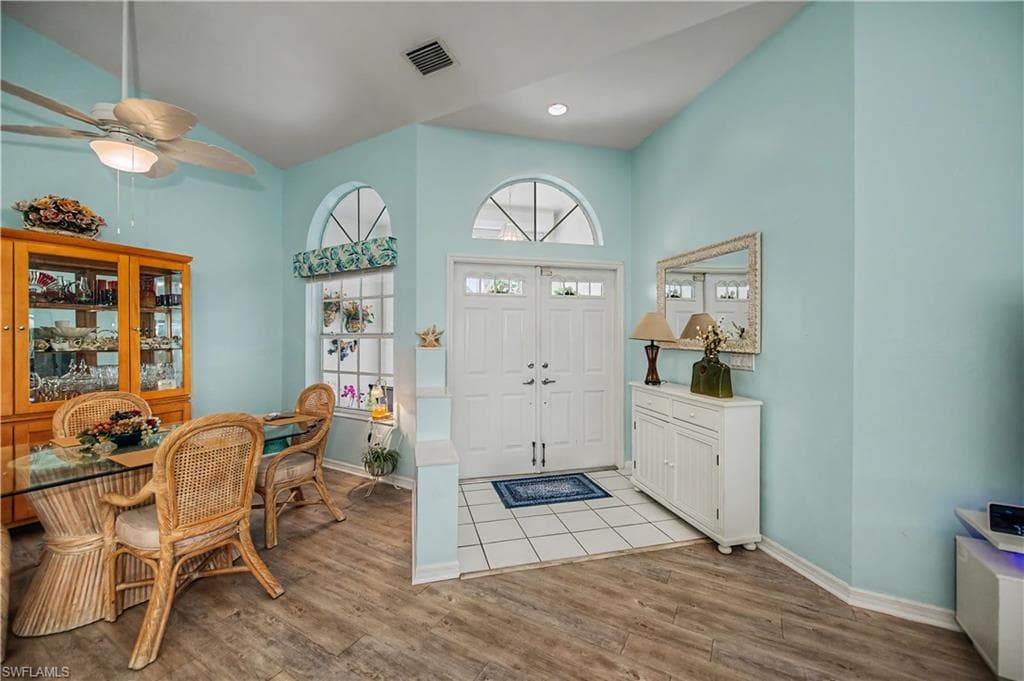Light-filled entry with double front doors, transom windows, and white tile flooring