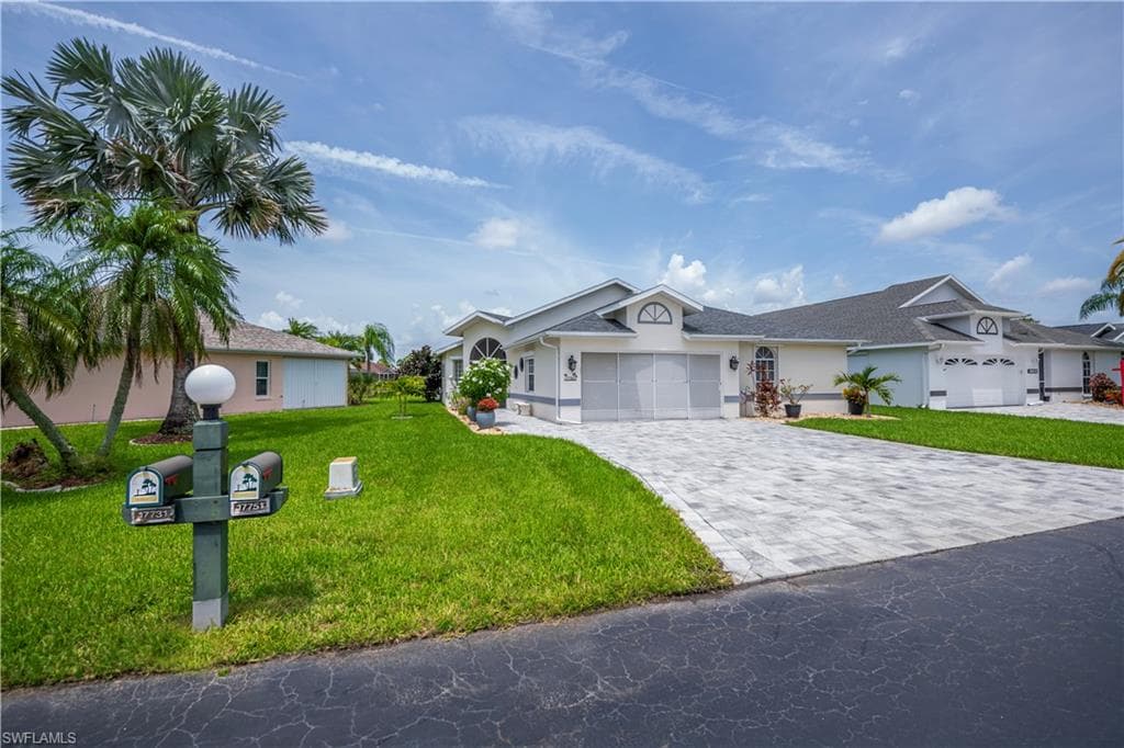 Contemporary residence featuring a paver driveway, an attached garage, and a lush green lawn