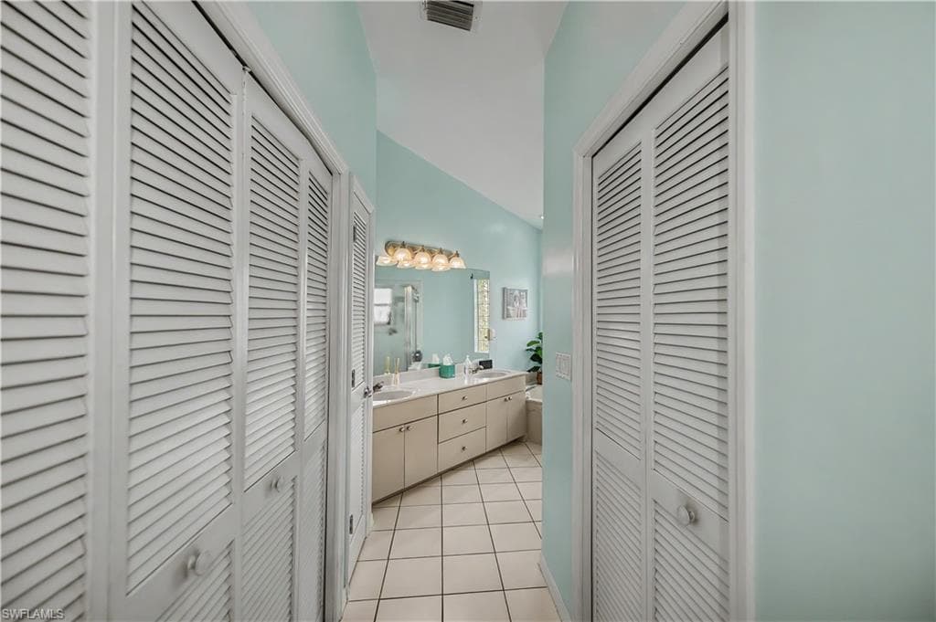 Double louvered doors framing a tiled hallway with a vaulted ceiling