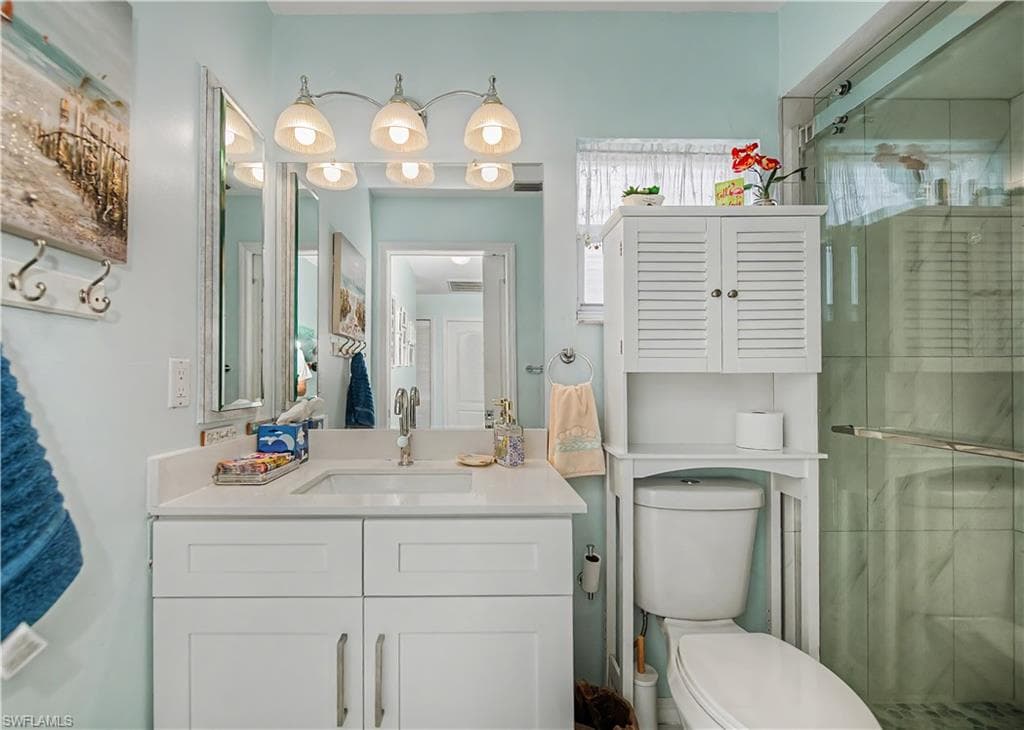 Bathroom featuring a white vanity with a rectangular undermount sink, a stone-finish countertop, and a four-light fixture