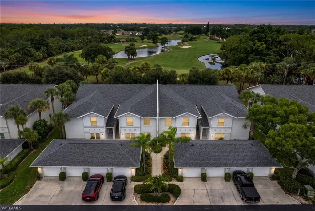 Aerial perspective showcasing multiple two-story townhomes with dark shingle roofs, white exteriors, and individual garage access