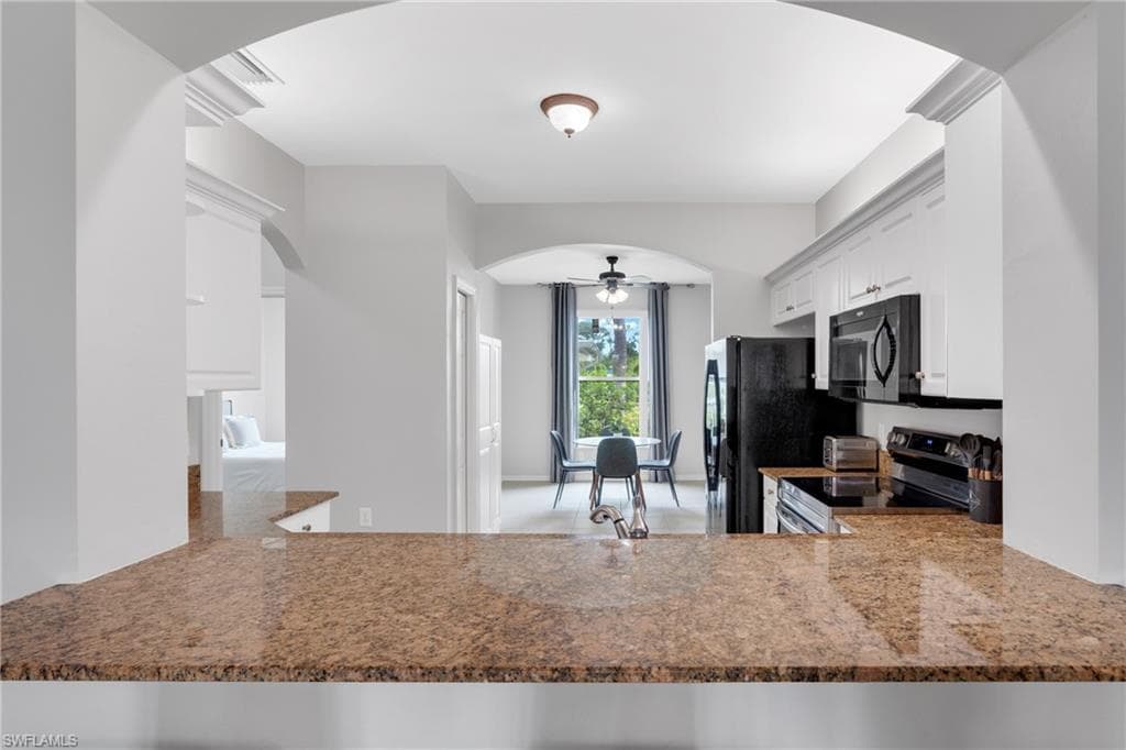 Kitchen featuring granite-style countertops, white cabinetry, and black appliances