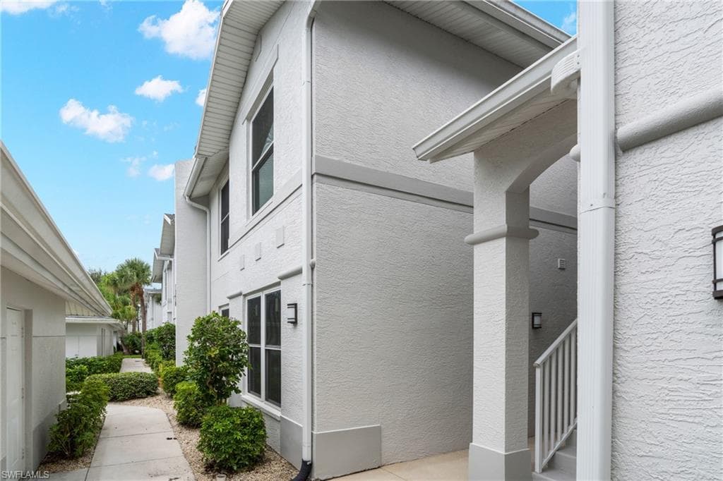 Stucco exterior featuring multiple windows and a covered entry with columns
