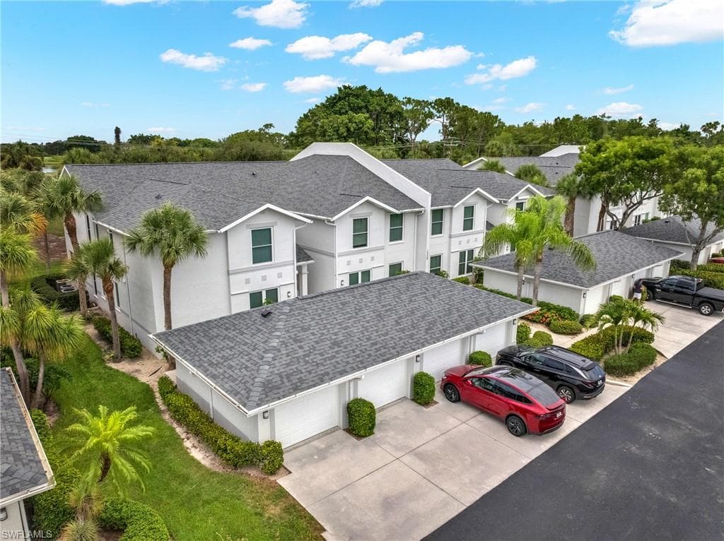 stucco townhomes featuring dark gray shingle roofing