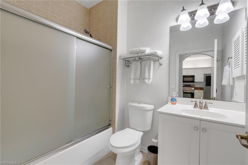 Bathroom featuring a white vanity with integrated sink, brushed nickel faucet, and a large mirror