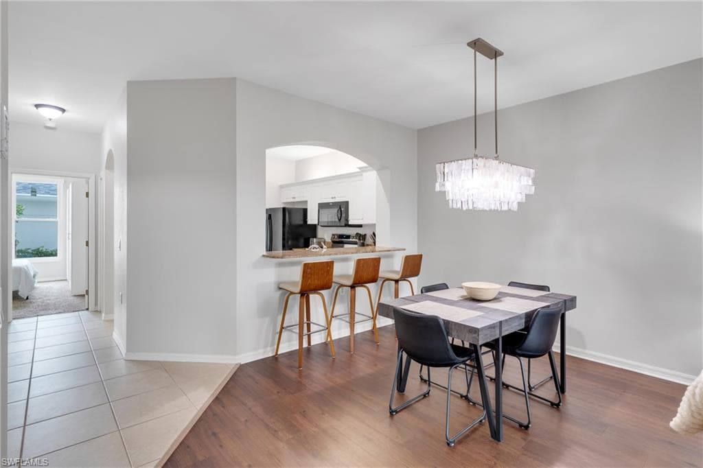 Dining area featuring a contemporary linear chandelier and wood-finish flooring