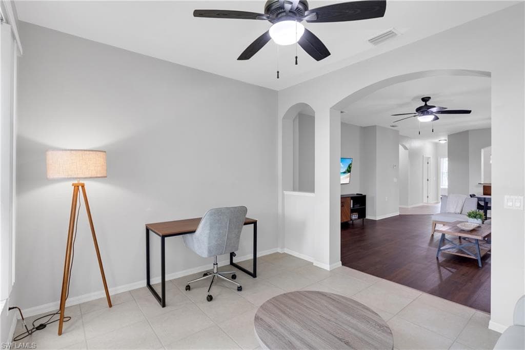 Open-concept interior featuring light gray wall paint, a ceiling fan with integrated lighting, and arched doorways