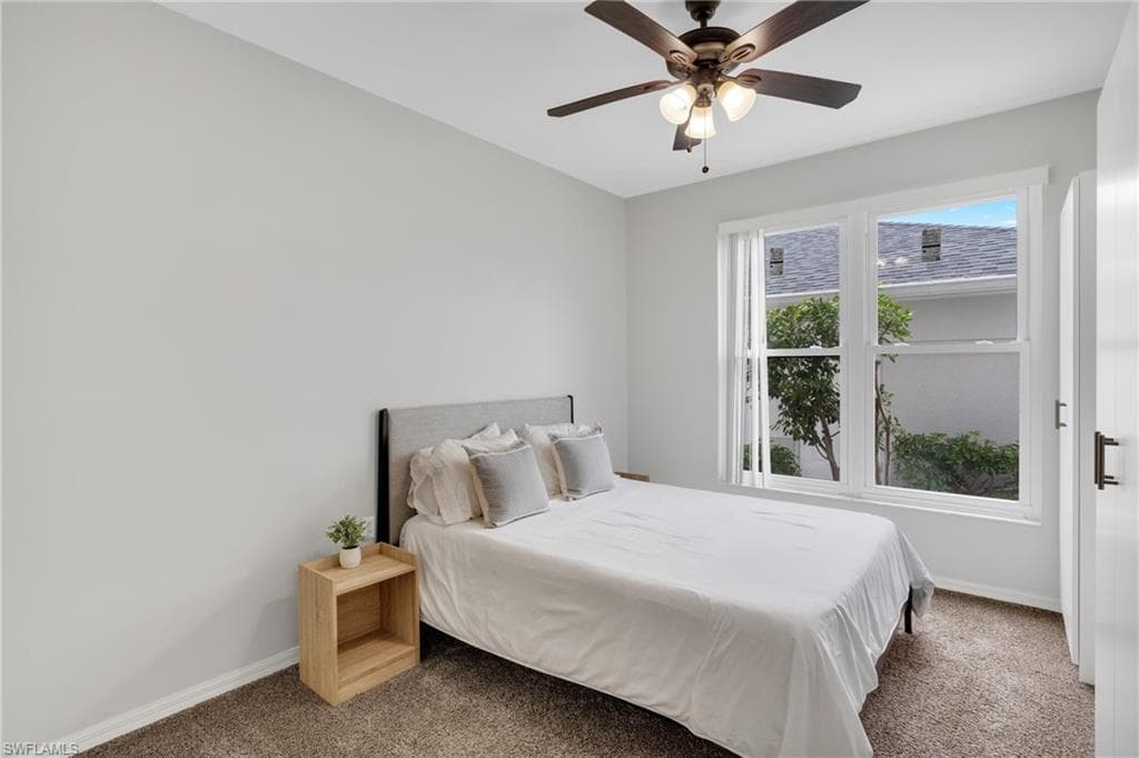 Carpeted room with a ceiling fan, a window with white blinds, and a built-in closet with dark hardware