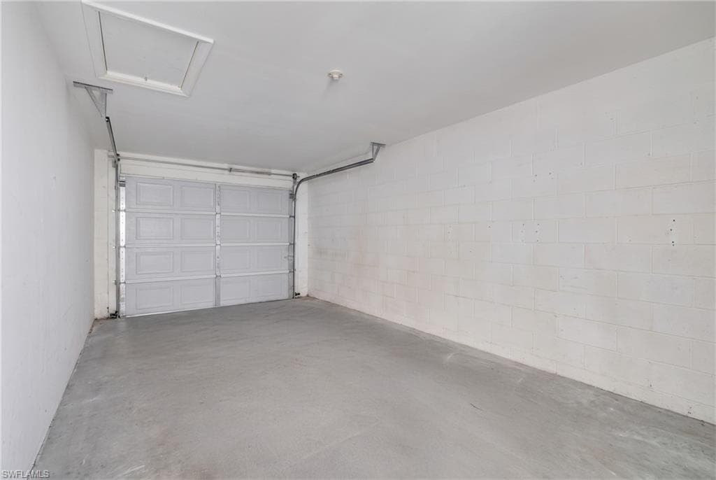 Single-car garage with a paneled overhead door, concrete flooring, and painted cinder block walls