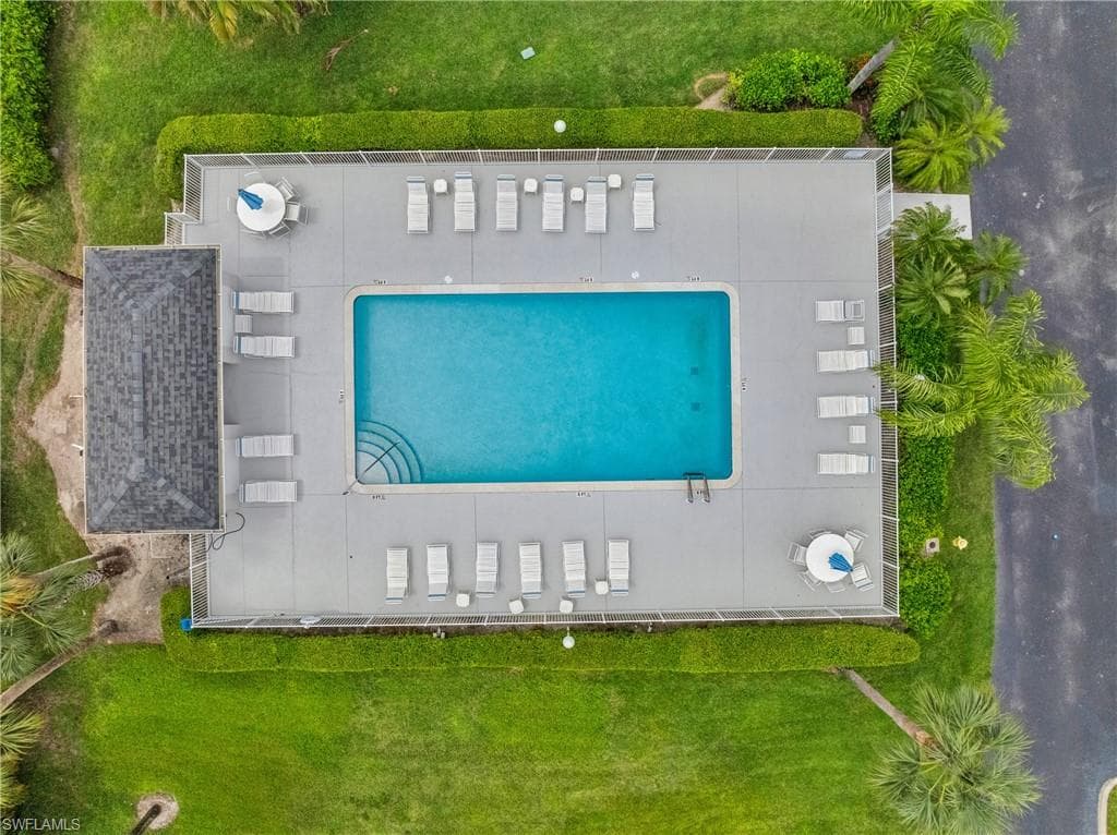 Rectangular swimming pool with integrated steps, surrounded by a concrete deck and a screen enclosure