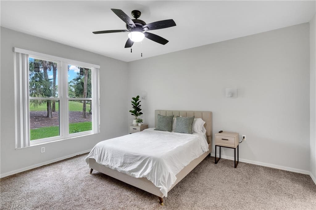 Bright interior room featuring a large window with white blinds, a ceiling fan with integrated lighting, and neutral-toned wall-to-wall carpeting