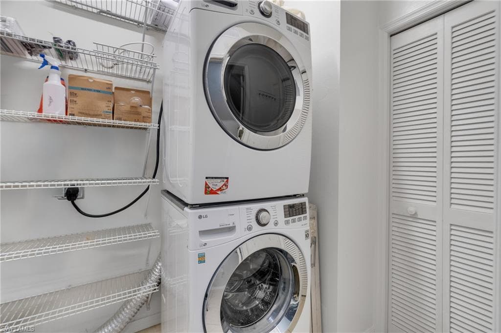 Dedicated laundry area featuring a stacked washer and dryer, adjacent to white louvered bifold doors