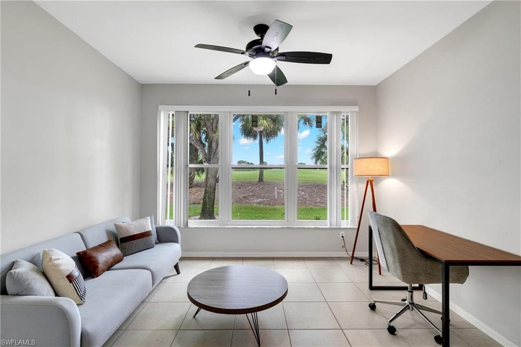 Spacious room featuring a multi-pane window overlooking green space, a ceiling fan with integrated lighting, and tile flooring