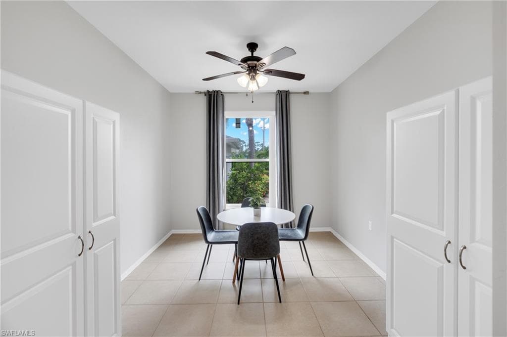 Dining area featuring a central window, ceiling fan with integrated lighting, and tile flooring